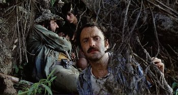 Movie still from “Cannibal Holocaust” (1980), directed by Ruggero Deodato – A group of men sitting in the bushes; Close Up shot, Low angle