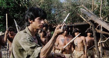 Movie still from “Cannibal Holocaust” (1980), directed by Ruggero Deodato – A group of people standing in a field; Medium shot, Over the shoulder angle