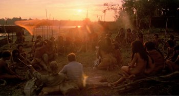 Movie still from “Cannibal Holocaust” (1980), directed by Ruggero Deodato – A group of people sitting on the ground at sunset; Wide shot, High angle