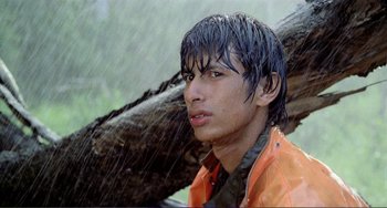 Movie still from “Cannibal Holocaust” (1980), directed by Ruggero Deodato – A young man in an orange rain jacket standing in the rain; Close Up shot, Low angle
