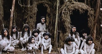 Movie still from “Cannibal Holocaust” (1980), directed by Ruggero Deodato – A group of people sitting next to each other in front of a tree; Wide shot, High angle