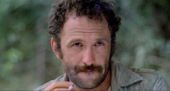 Movie still from “Cannibal Holocaust” (1980), directed by Ruggero Deodato – A person smoking a cigarette; Close Up shot, Low angle