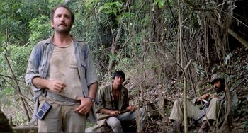 Movie still from “Cannibal Holocaust” (1980), directed by Ruggero Deodato – A group of people sitting in the woods; Medium shot, Low angle