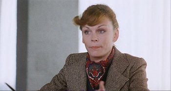 Movie still from “Cannibal Holocaust” (1980), directed by Ruggero Deodato – A woman in a jacket and a neck tie looks at the camera; Close Up shot, Over the shoulder angle