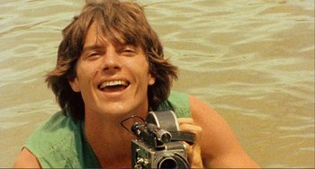 Movie still from “Cannibal Holocaust” (1980), directed by Ruggero Deodato – A man holding a camera in a body of water; Close Up shot, Low angle