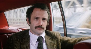 Movie still from “Cannibal Holocaust” (1980), directed by Ruggero Deodato – A man with a mustache sitting in the back seat of a car; Close Up shot, Low angle