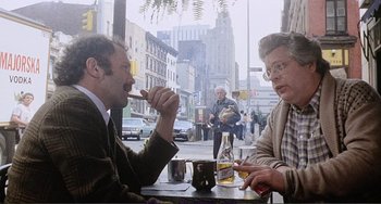 Movie still from “Cannibal Holocaust” (1980), directed by Ruggero Deodato – A man and a woman sitting at a table with drinks; Medium shot, Over the shoulder angle