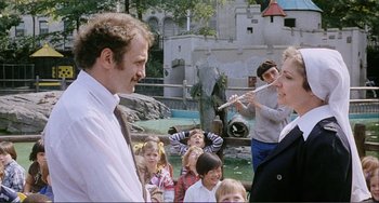 Movie still from “Cannibal Holocaust” (1980), directed by Ruggero Deodato – A man and a woman standing next to each other in front of a crowd; Medium shot, Over the shoulder angle
