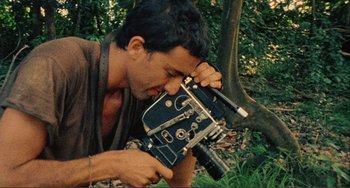 Movie still from “Cannibal Holocaust” (1980), directed by Ruggero Deodato – A man holding an old camera in his hands; Extreme Close Up shot, Low angle