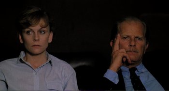 Movie still from “Cannibal Holocaust” (1980), directed by Ruggero Deodato – A man and a woman sitting next to each other in a dark room; Close Up shot, Over the shoulder angle