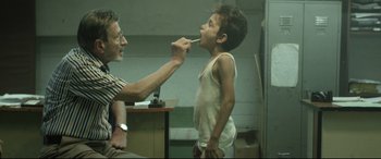 A man and a boy are brushing their teeth together
