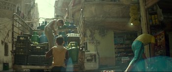 Movie still from “Capernaum” (2018), directed by Nadine Labaki – A man standing next to a building next to a gas tank; Wide shot, Over the shoulder angle