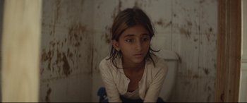 Movie still from “Capernaum” (2018), directed by Nadine Labaki – A young girl sitting on a toilet in a bathroom; Close Up shot, Over the shoulder angle