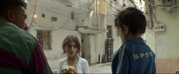 Movie still from “Capernaum” (2018), directed by Nadine Labaki – A young girl eating a sandwich while standing next to a boy; Close Up shot, Over the shoulder angle