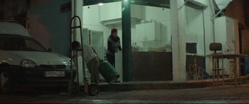 Movie still from “Capernaum” (2018), directed by Nadine Labaki – A woman in a red headscarf and a man in a black shirt; Wide shot, Low angle