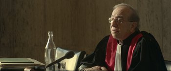 Movie still from “Capernaum” (2018), directed by Nadine Labaki – An old man wearing a red and black robe; Medium shot, Over the shoulder angle