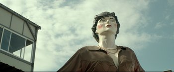 Movie still from “Capernaum” (2018), directed by Nadine Labaki – A statue of a woman in a brown shirt and a hat; Medium shot, Low angle