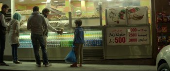 Movie still from “Capernaum” (2018), directed by Nadine Labaki – A child standing in front of a display of drinks; Wide shot, Over the shoulder angle