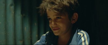 Movie still from “Capernaum” (2018), directed by Nadine Labaki – A young boy is smiling for the camera; Close Up shot, Over the shoulder angle