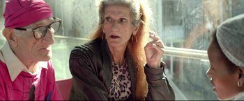 Movie still from “Capernaum” (2018), directed by Nadine Labaki – An older woman with long red hair smoking a cigarette; Close Up shot, Over the shoulder angle