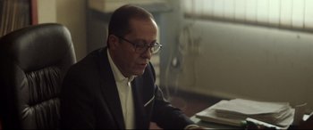 Movie still from “Capernaum” (2018), directed by Nadine Labaki – A man in a suit and glasses looking down at a laptop; Close Up shot, Low angle