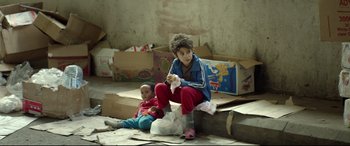 Movie still from “Capernaum” (2018), directed by Nadine Labaki – Two young children sitting on the ground in a room; Medium shot, Over the shoulder angle