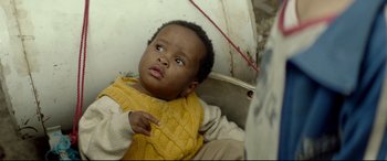 Movie still from “Capernaum” (2018), directed by Nadine Labaki – A young boy wearing a yellow sweater and sitting on the ground; Close Up shot, Over the shoulder angle