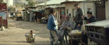 Movie still from “Capernaum” (2018), directed by Nadine Labaki – A group of people standing on a dirt road; Wide shot, Over the shoulder angle