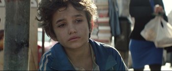 Movie still from “Capernaum” (2018), directed by Nadine Labaki – A young boy is sitting in front of a stack of books; Close Up shot, Over the shoulder angle