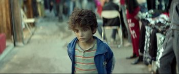 Movie still from “Capernaum” (2018), directed by Nadine Labaki – A young boy is standing in a crowd of people; Close Up shot, Over the shoulder angle
