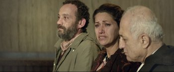 Movie still from “Capernaum” (2018), directed by Nadine Labaki – A man and a woman crying in front of another man; Medium shot, Over the shoulder angle