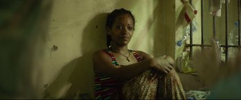 Movie still from “Capernaum” (2018), directed by Nadine Labaki – A woman sitting against a wall with her hands on her hips; Close Up shot, High angle