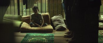 Movie still from “Capernaum” (2018), directed by Nadine Labaki – A young boy sitting on a couch in a room; Wide shot, Low angle