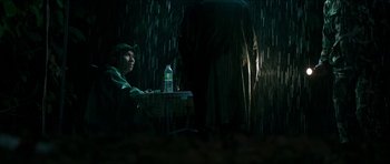 Movie still from “Cave Rescue” (2022), directed by Tom Waller – A man sitting at a table in the dark; Medium shot, Low angle