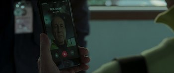 Movie still from “Cave Rescue” (2022), directed by Tom Waller – A person holding up a cell phone to take a picture of an old man's face; Close Up shot, High angle