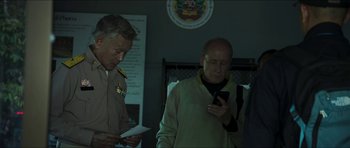 Movie still from “Cave Rescue” (2022), directed by Tom Waller – A group of men standing next to each other looking at their phones; Medium shot, Low angle