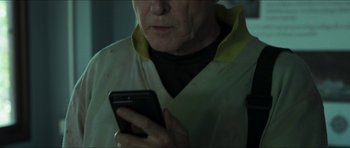 Movie still from “Cave Rescue” (2022), directed by Tom Waller – An older man holding a cell phone in his hands; Close Up shot, Low angle