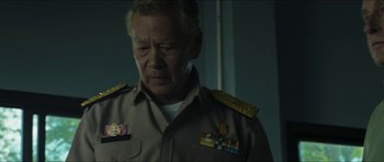 Movie still from “Cave Rescue” (2022), directed by Tom Waller – An older man wearing a military uniform looking down; Medium shot, Over the shoulder angle