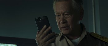Movie still from “Cave Rescue” (2022), directed by Tom Waller – An older man looking at a cell phone; Close Up shot, Low angle