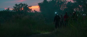 Movie still from “Cave Rescue” (2022), directed by Tom Waller – Two people are walking through a field at night; Extreme Wide shot, Low angle