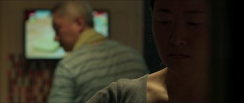 Movie still from “Cave Rescue” (2022), directed by Tom Waller – A woman sitting in front of a man on a couch; Close Up shot, Over the shoulder angle