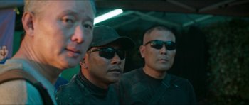 Movie still from “Cave Rescue” (2022), directed by Tom Waller – A group of men wearing sunglasses and hats; Close Up shot, Over the shoulder angle