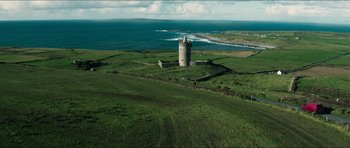 Movie still from “Cave Rescue” (2022), directed by Tom Waller – An aerial view of a castle on a hill overlooking the ocean; Extreme Wide shot, High angle