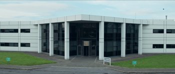 Movie still from “Cave Rescue” (2022), directed by Tom Waller – A building that has many windows on the outside of the building; Extreme Wide shot, Low angle