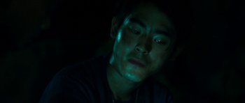 Movie still from “Cave Rescue” (2022), directed by Tom Waller – A young man is sitting in a dark room; Close Up shot, Over the shoulder angle