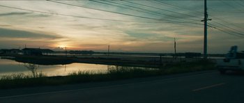 Movie still from “Cave Rescue” (2022), directed by Tom Waller – A view of a body of water at sunset; Extreme Wide shot, Low angle