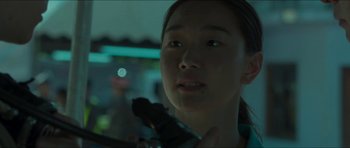 Movie still from “Cave Rescue” (2022), directed by Tom Waller – A young woman holding a camera in a room; Close Up shot, Over the shoulder angle