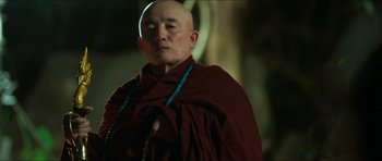 Movie still from “Cave Rescue” (2022), directed by Tom Waller – A man in a monk's robe with a rosary; Close Up shot, Low angle