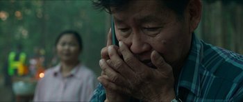 Movie still from “Cave Rescue” (2022), directed by Tom Waller – An older man holding a cell phone to his face; Close Up shot, Over the shoulder angle