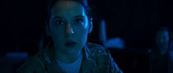 Movie still from “Cave Rescue” (2022), directed by Tom Waller – A woman in military fatigues stares into the camera; Close Up shot, Over the shoulder angle